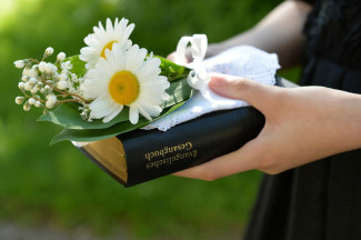 Konfirmandin mit Gesangbuch und Blumen